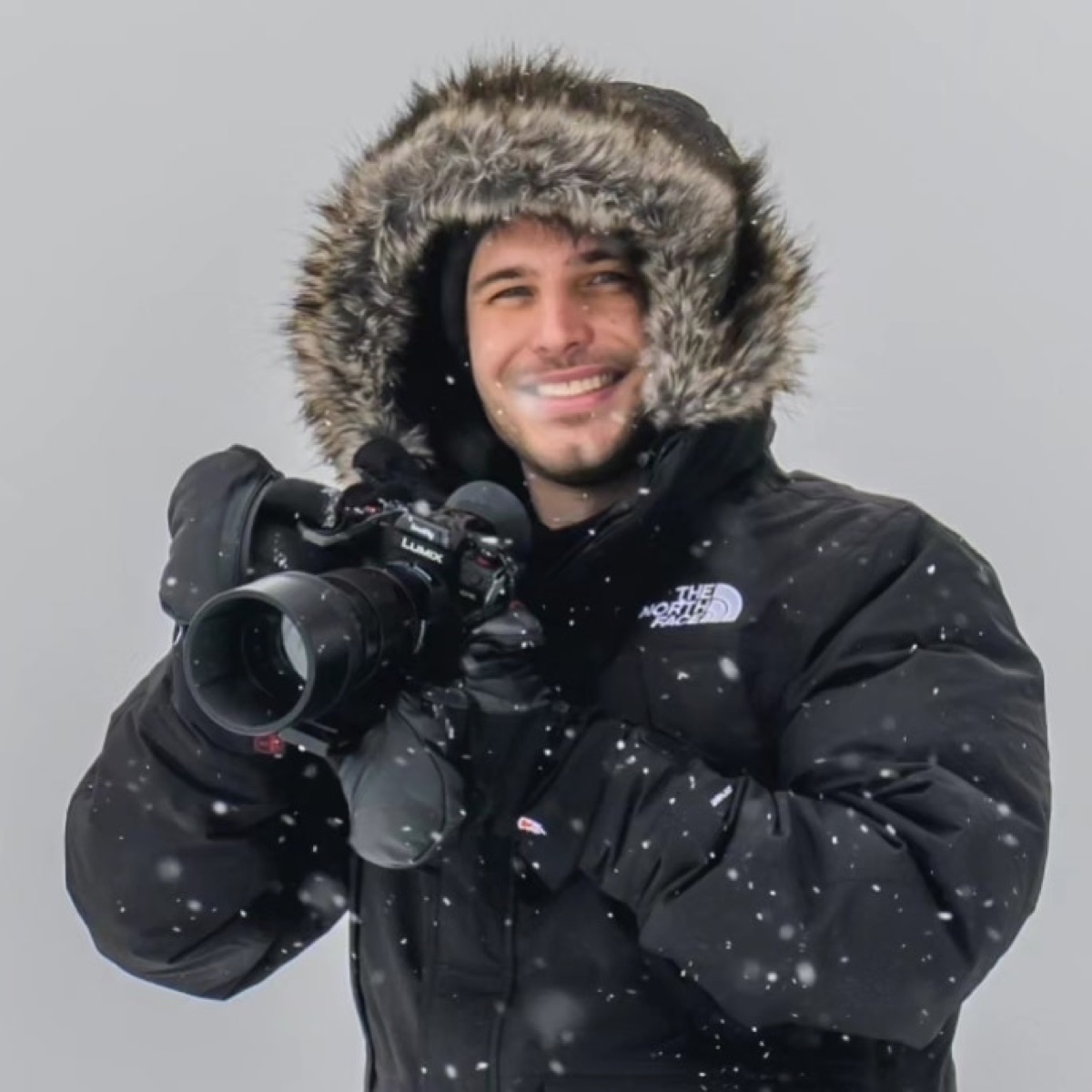 Corbin Kinsch holding his camera in falling snow